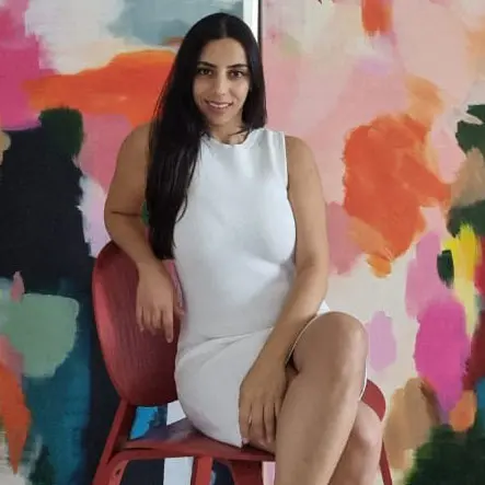 Interior designer posing in front of colorful abstract artwork