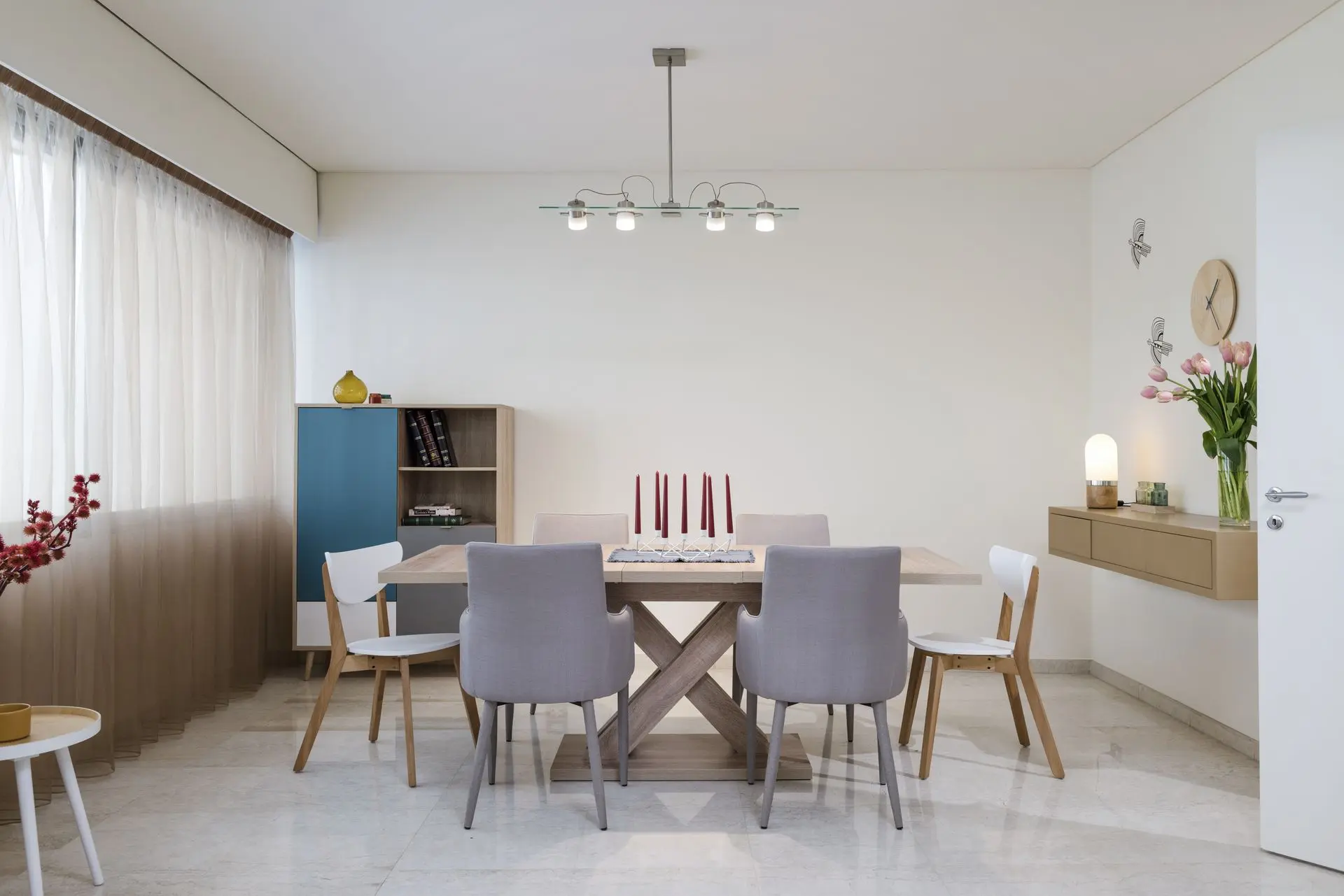 Minimalist dining room with modern white chairs, light wooden table, and pendant lights