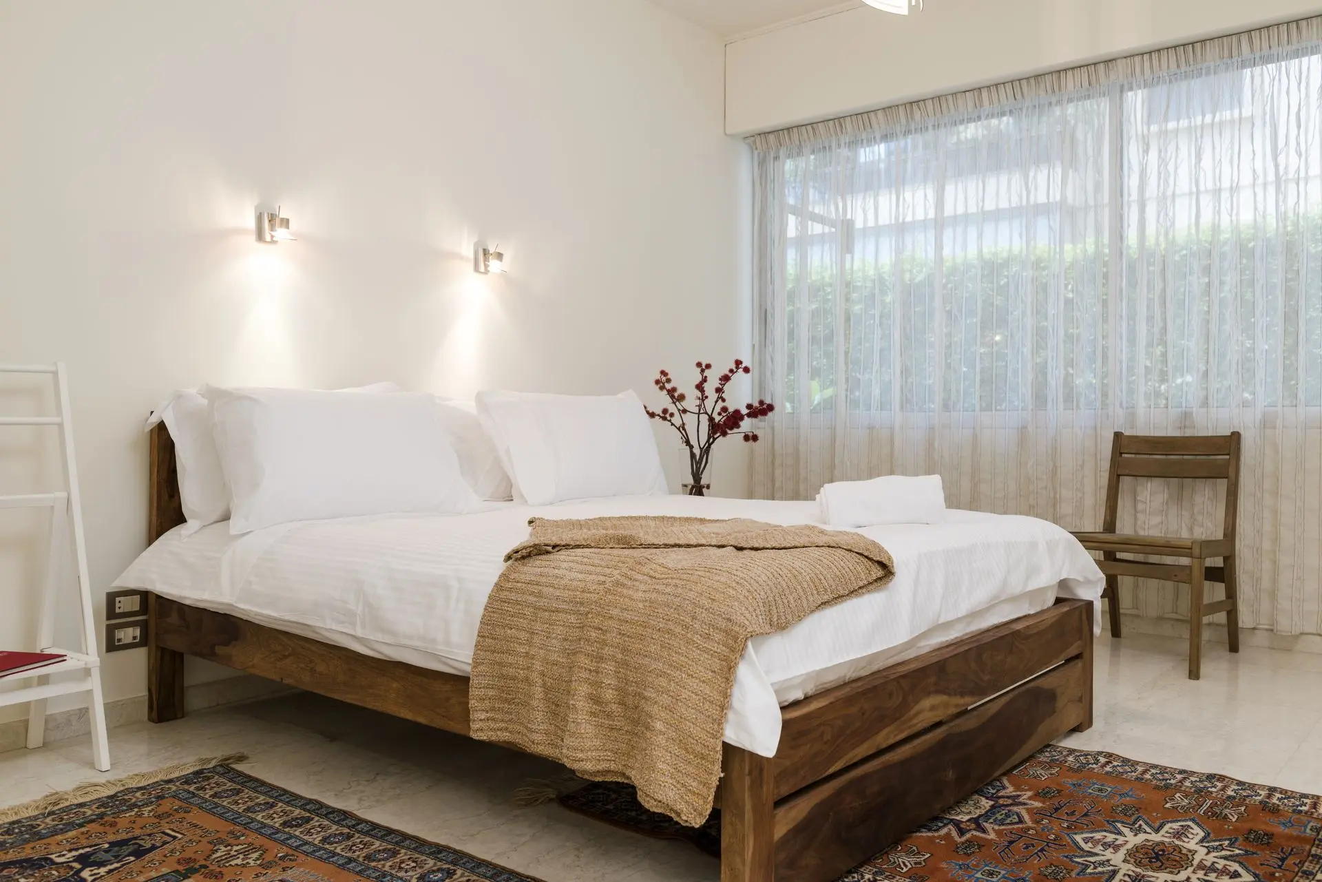 alt=&#34;Softly lit bedroom with flower arrangement and textured throw&#34;